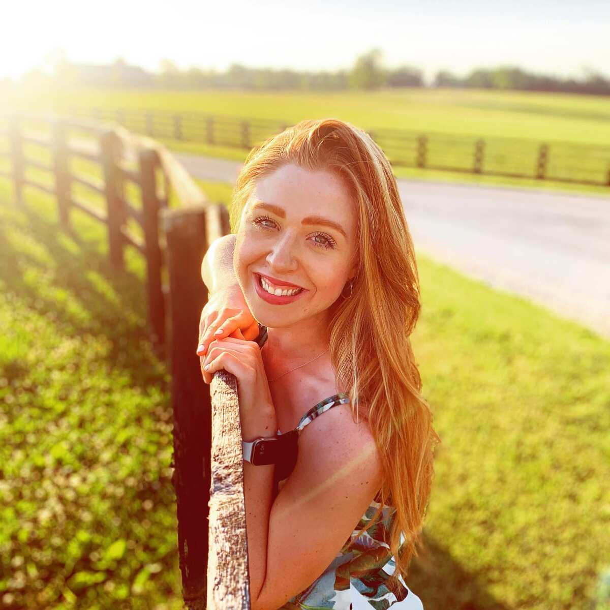 Naomi Hurdle, woman with long dark blonde hair, leaning on board fence