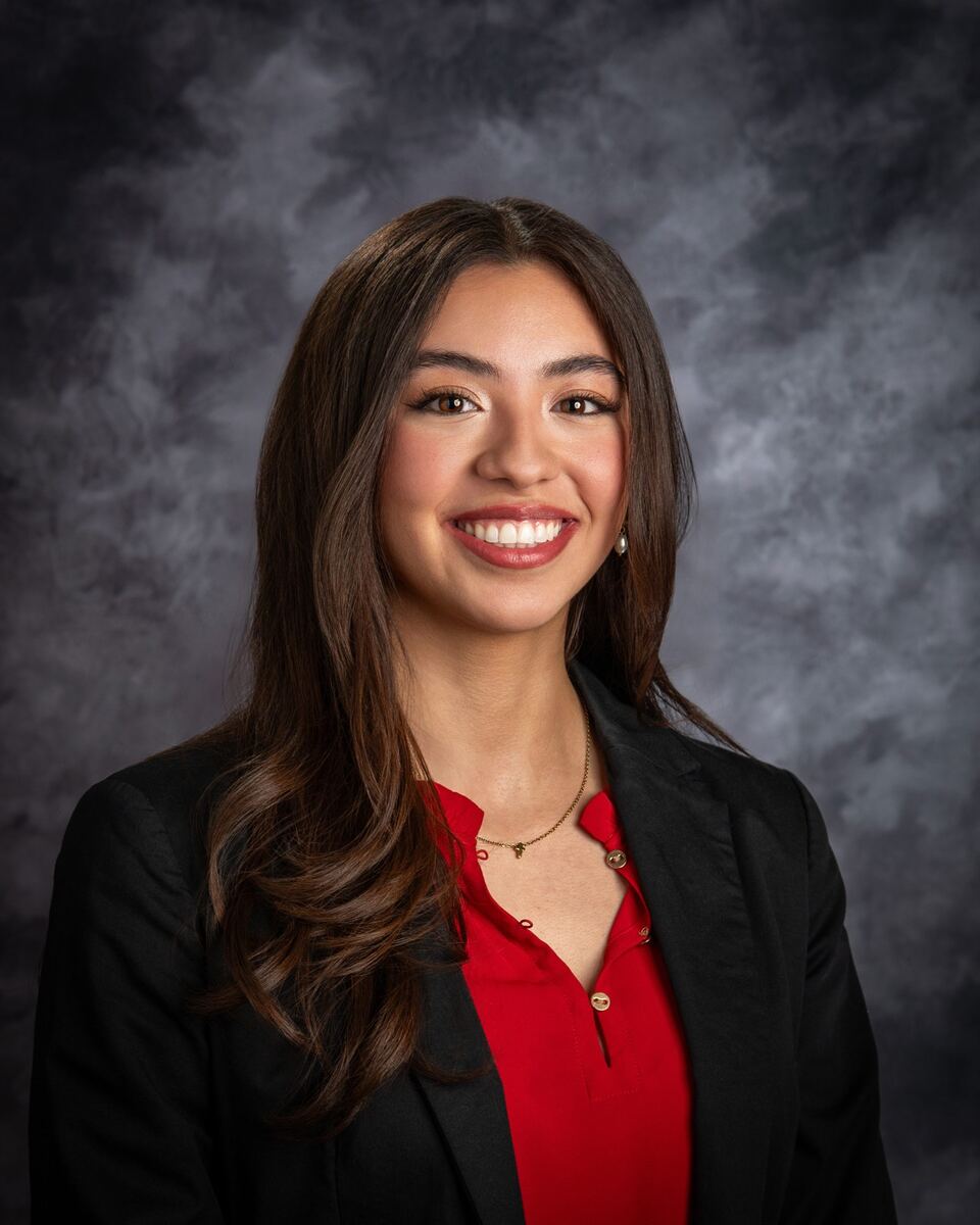 Paola Castro, in red shirt and black blazer