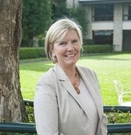 Woman with short blonde hair in tan suit jacket