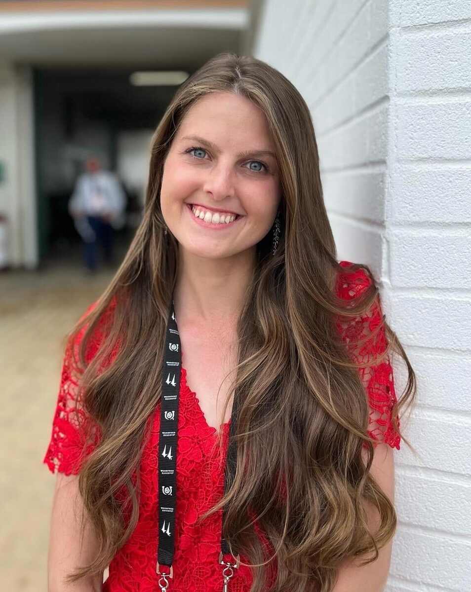 Sarah Gordon, woman with long brown hair, red shirt, and lanyard
