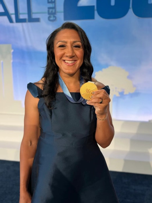 woman in blue dress with long dark hair holding gold medal